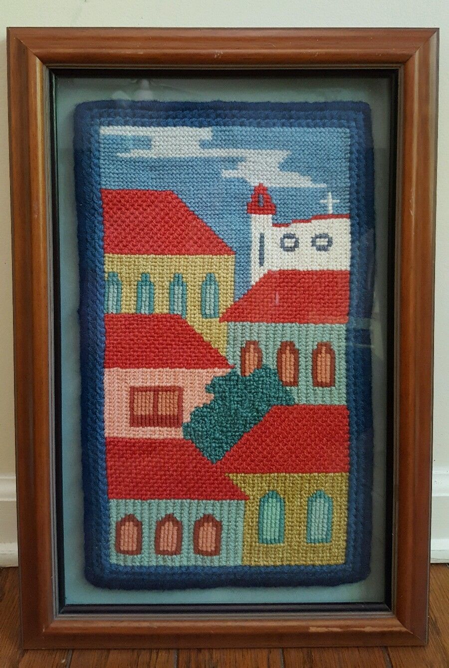 Framed needlepoint knitting artwork of  church and buildings skyline